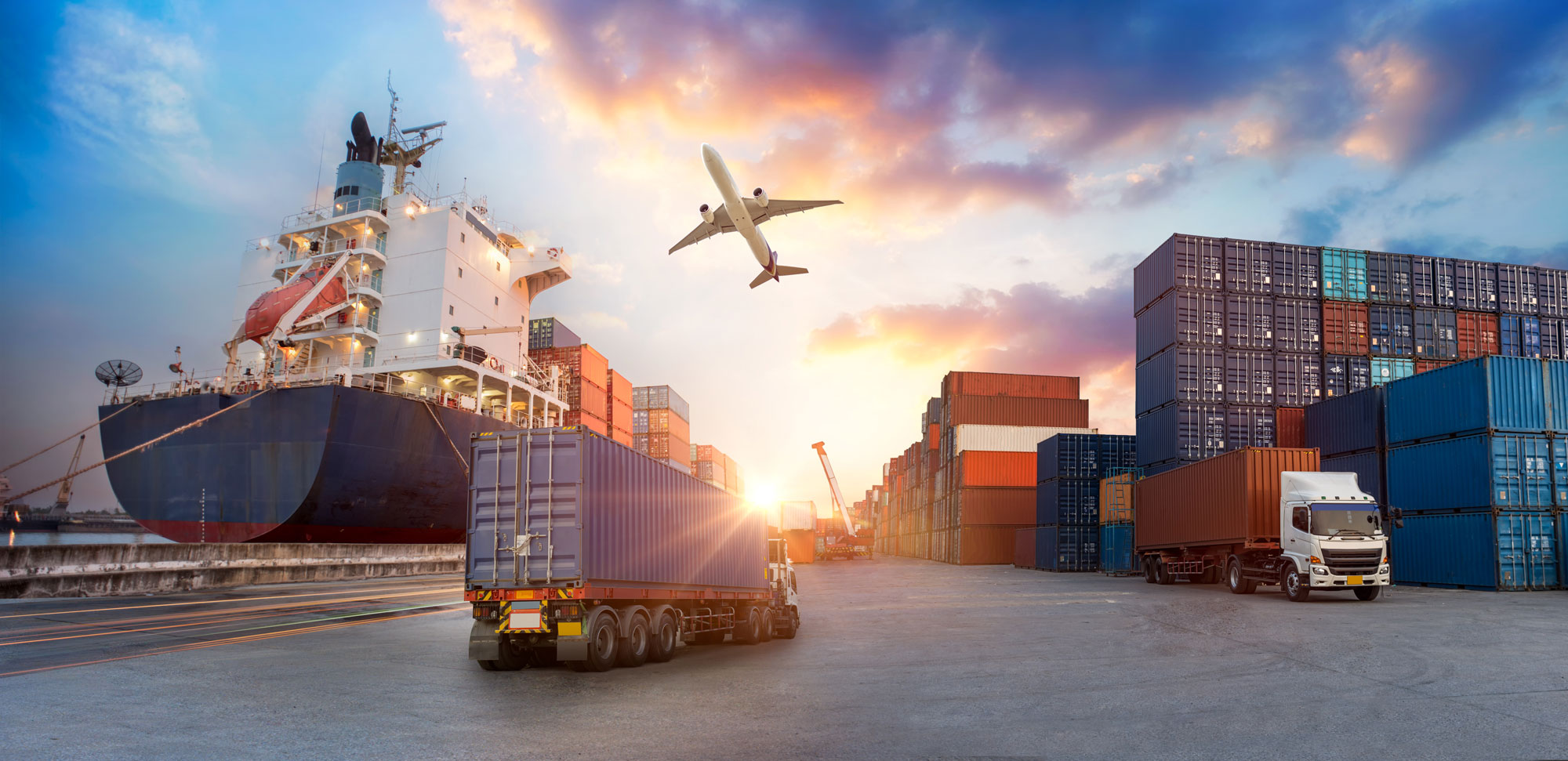 Container port with cargo ship, truck, and plane at sunset